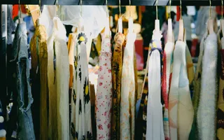 Étal de vide-grenier vintage à Angers avec vêtements, sacs et bijoux anciens exposés sur des tréteaux.